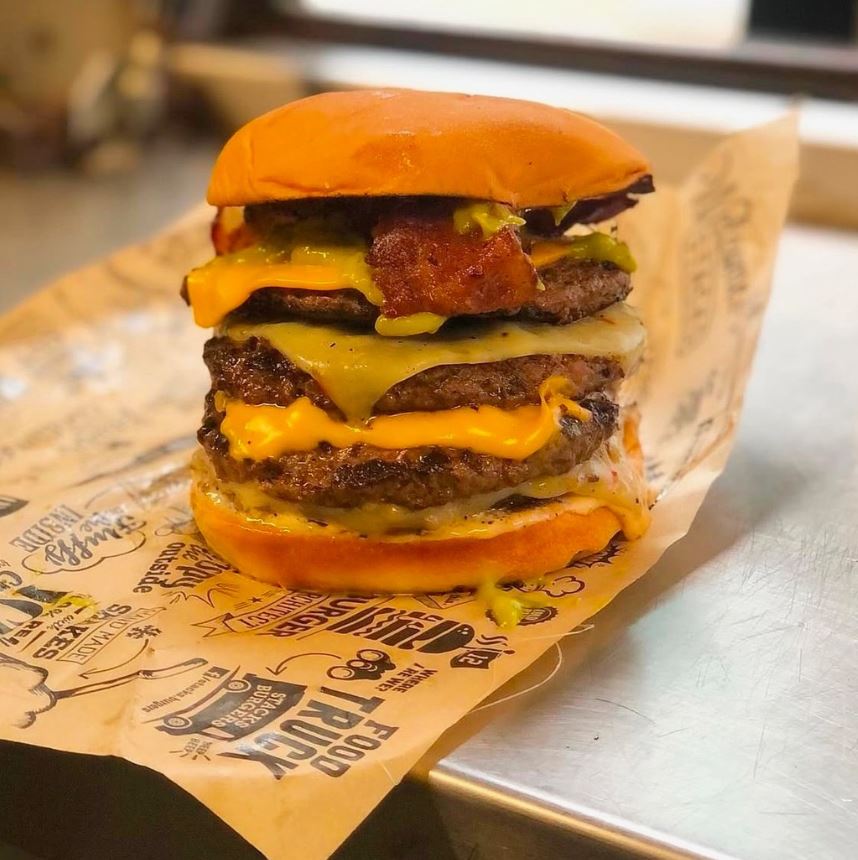 Stacked cheeseburger served on custom printed greaseproof burger paper for cleaner food presentation